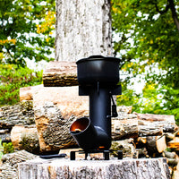 Vista della stufa a razzo con legna  da stufa in fondo nel bosco